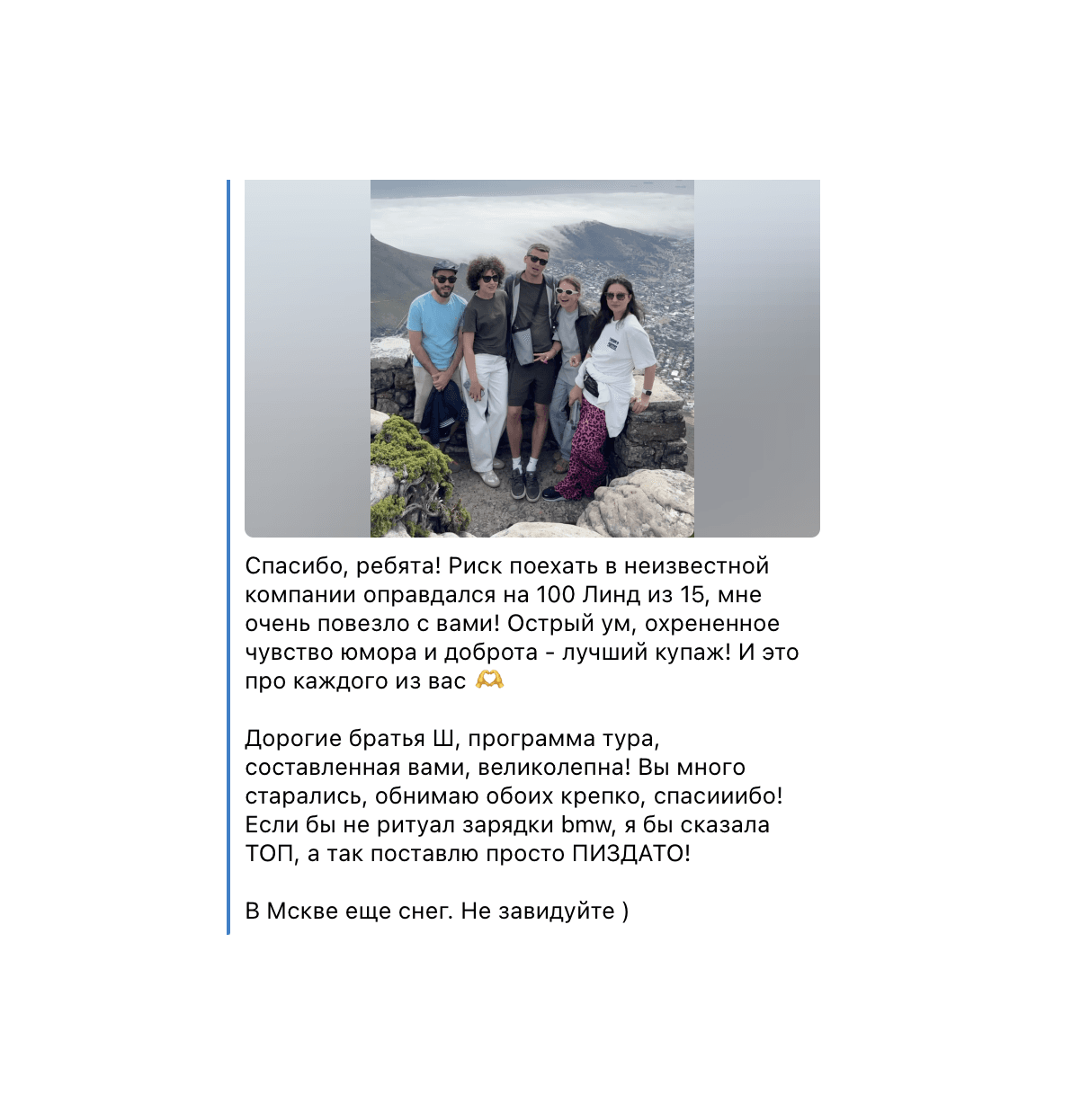 Five people posing on a rocky overlook above a city with Russian text underneath.
